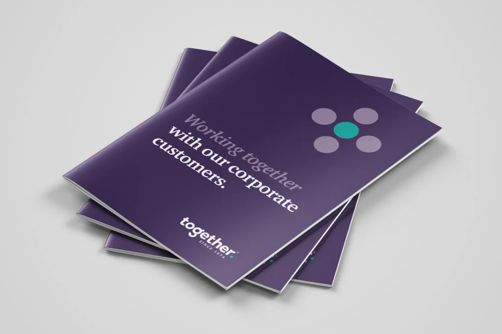 A pile of 3 corporate brochures designed by Mode=Create for a financial lender. The brochure on the top of the pile reveals the front cover which is mainly aubergine and has the title 'Working together with our corporate customers.'